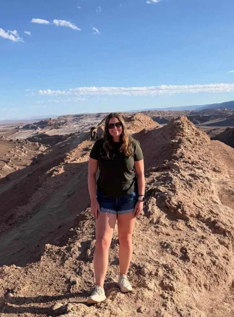 Kaitlin standing on a ridge in the Valle de la Luna with the vast Atacama Desert stretching behind, Chile