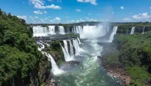 Iguazu Falls cascading across multiple drops into churning white rapids surrounded by dense rainforest, Brazilian side