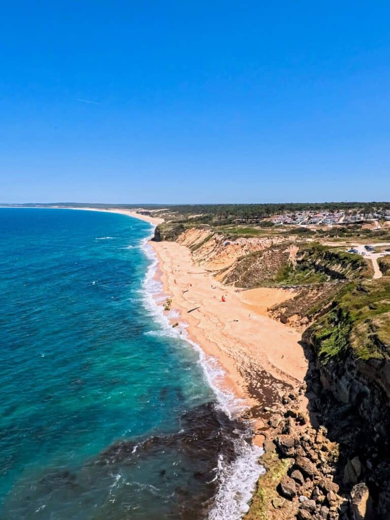 Aerial view of the Algarve coastline with turquoise Atlantic water, terracotta cliffs, and a long sandy beach, Portugal