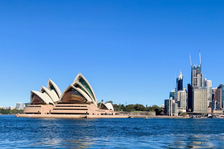 Sydney Opera House seen from the harbor with the city skyline and deep blue sky behind, New South Wales, Australia