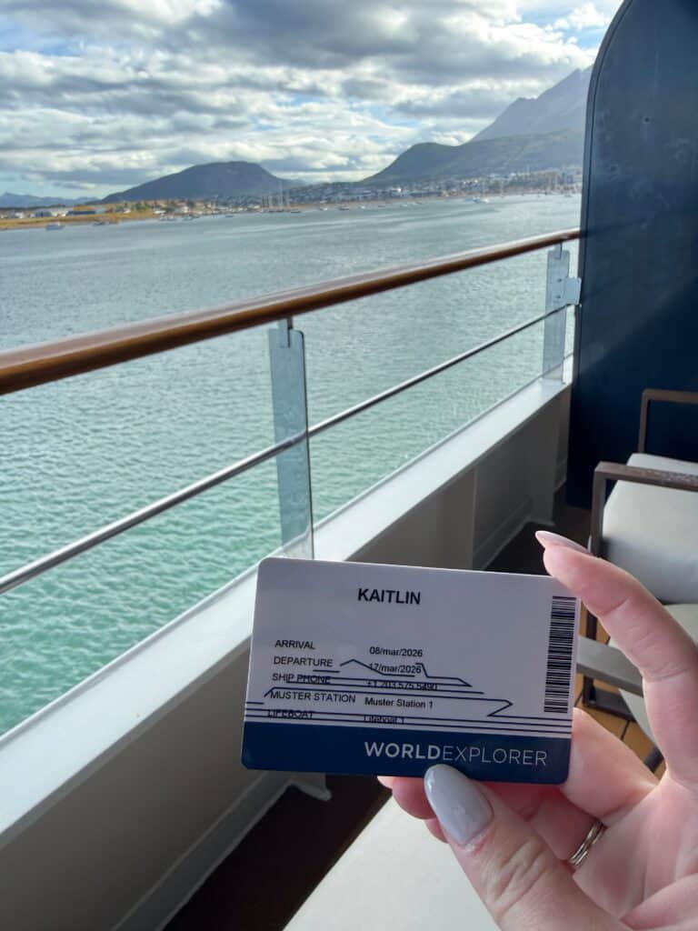 Holding the cabin key card after booking a last-minute Antarctica deal, Ushuaia in the background