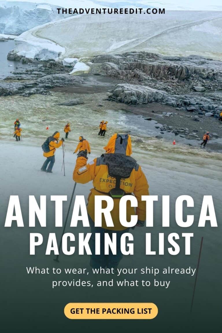 Travelers in yellow expedition parkas walking across a snow-covered landing site in Antarctica during a shore excursion