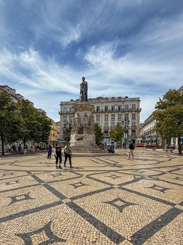 Praça Luís de Camões in Chiado, Lisbon, with a statue of the poet and a yellow tram passing behind.