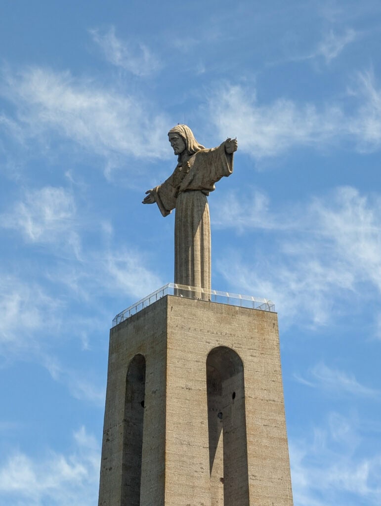 Cristo Rei statue in Almada, arms outstretched over the Tagus River near the 25 de Abril Bridge.